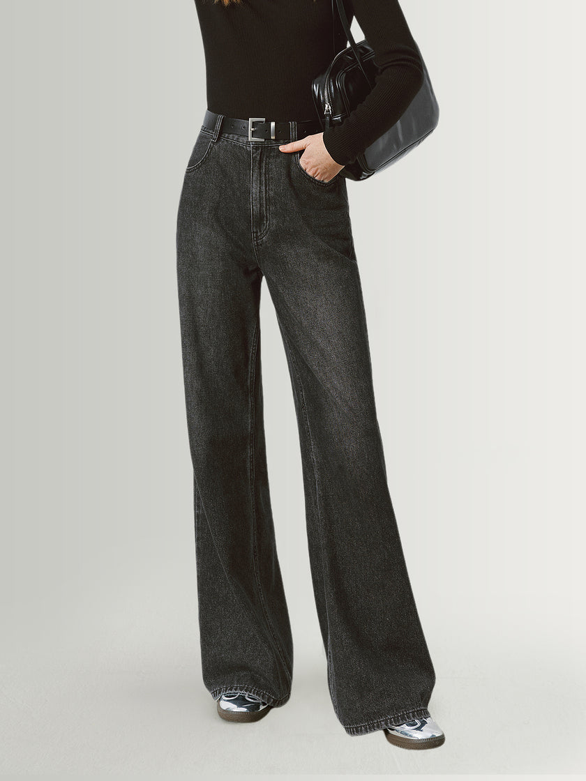 Person wearing black high-waisted jeans on a light gray background