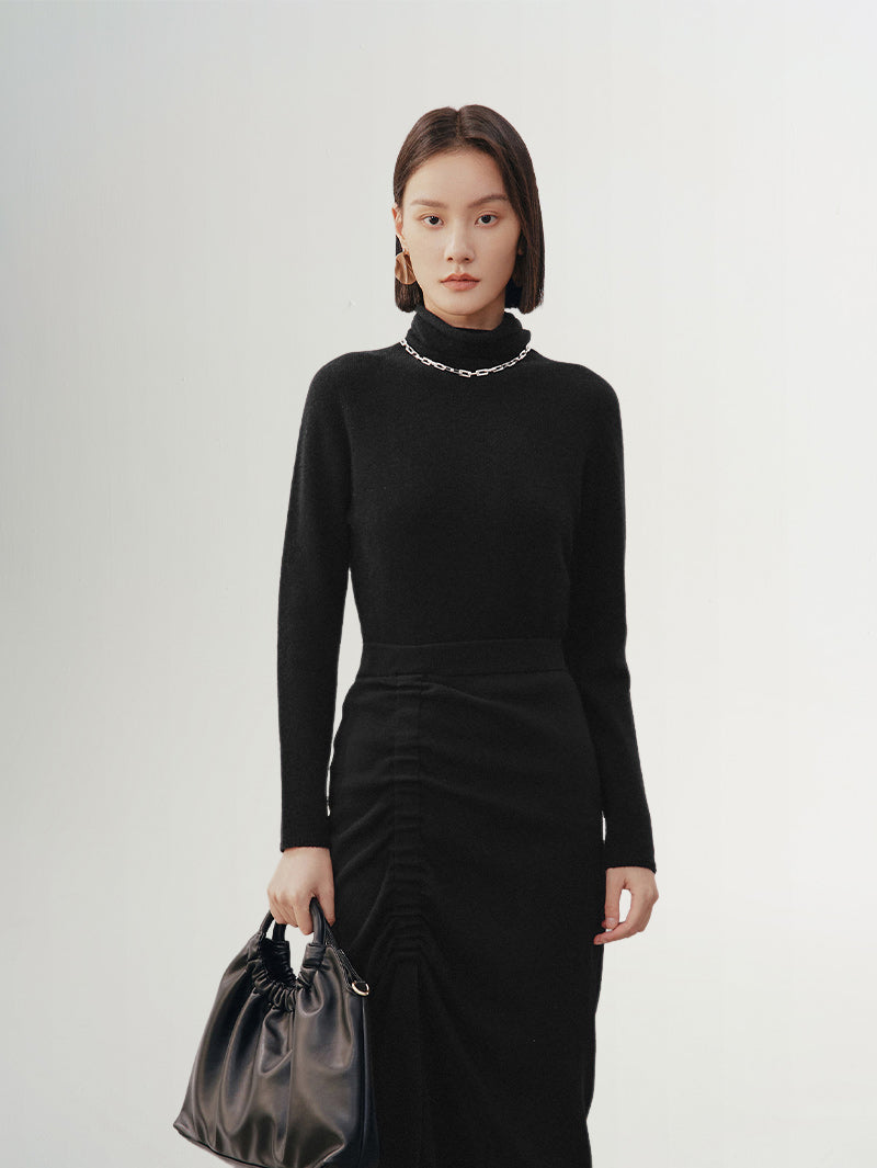 Woman wearing a black high neck layering cashmere sweater, with a stylish handbag, showcasing luxurious comfort.