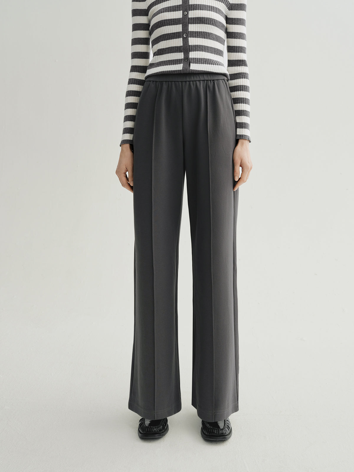 Person wearing black wide-leg pants with a striped sweater on a white background