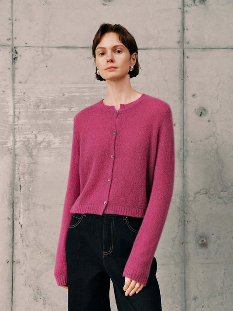 Silk-Cashmere Cardigan in vibrant pink, styled with dark jeans against a textured backdrop.