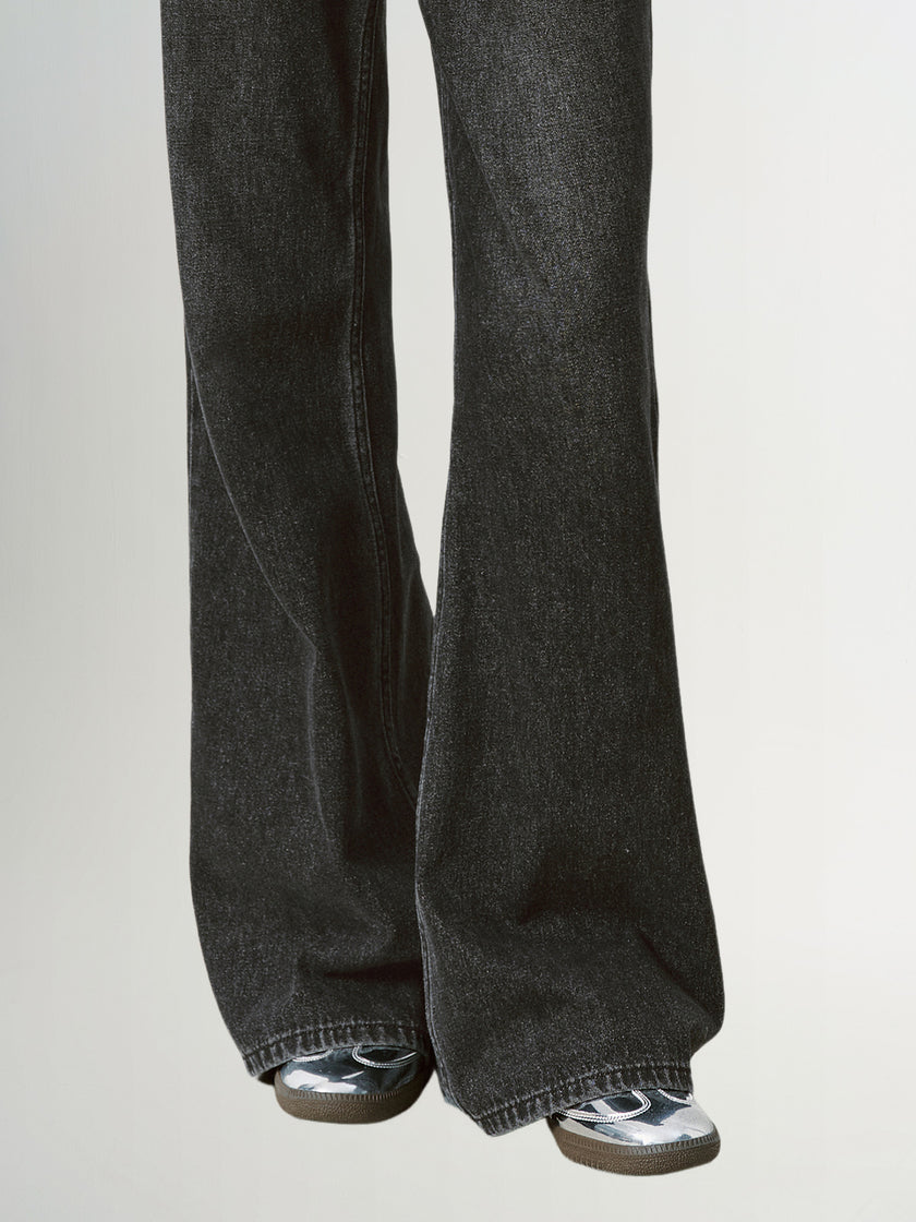 Black flared jeans worn by a person on a light gray background