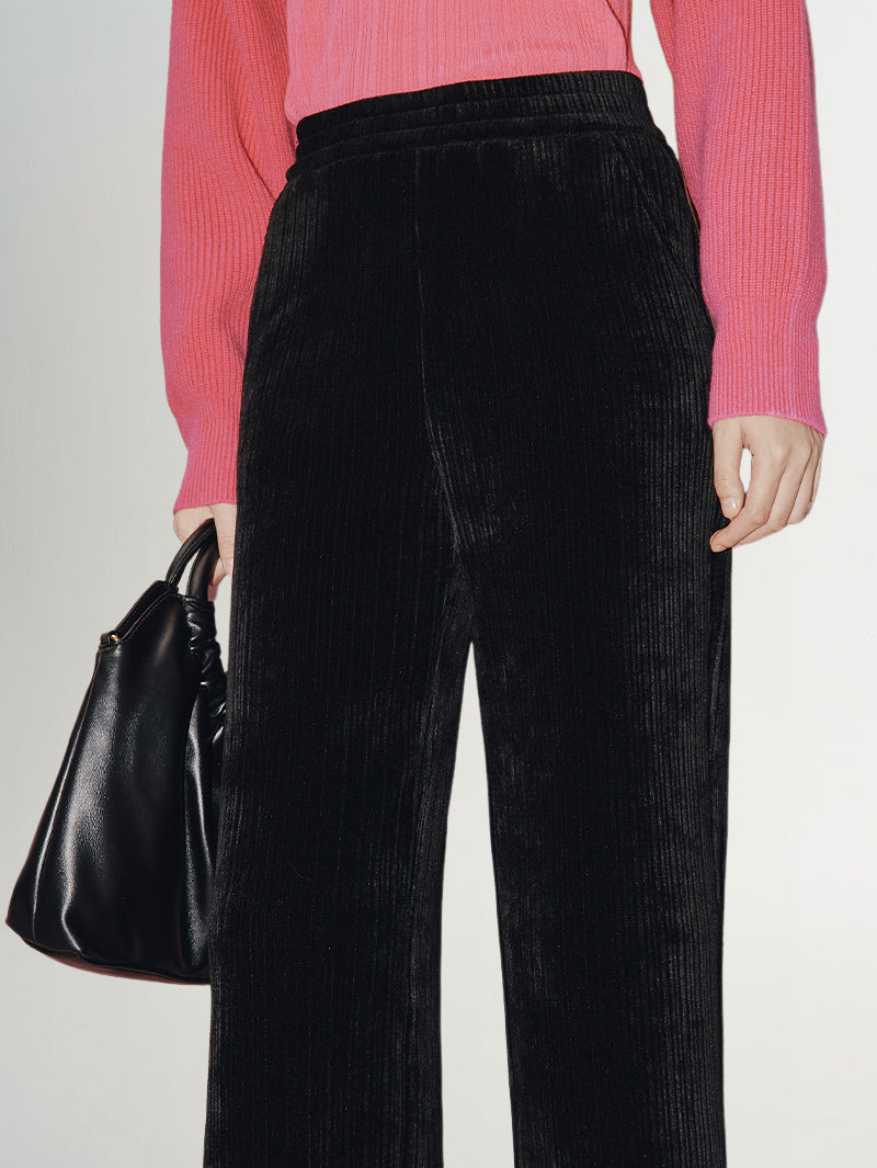 Wide Leg Trousers in rich velvet-like black fabric with a high-rise elastic waistband, paired with a pink top.