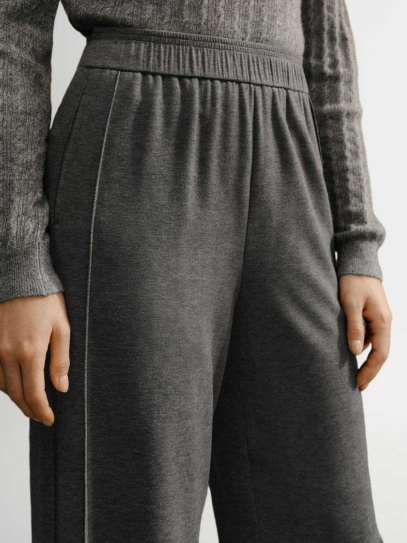 Person wearing gray sweatpants and a matching sweater on a light background