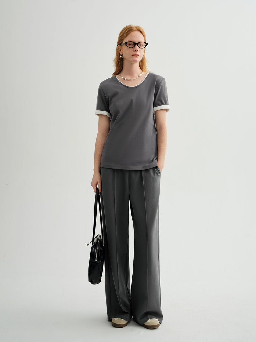 Woman wearing a gray t-shirt and black pants against a white background