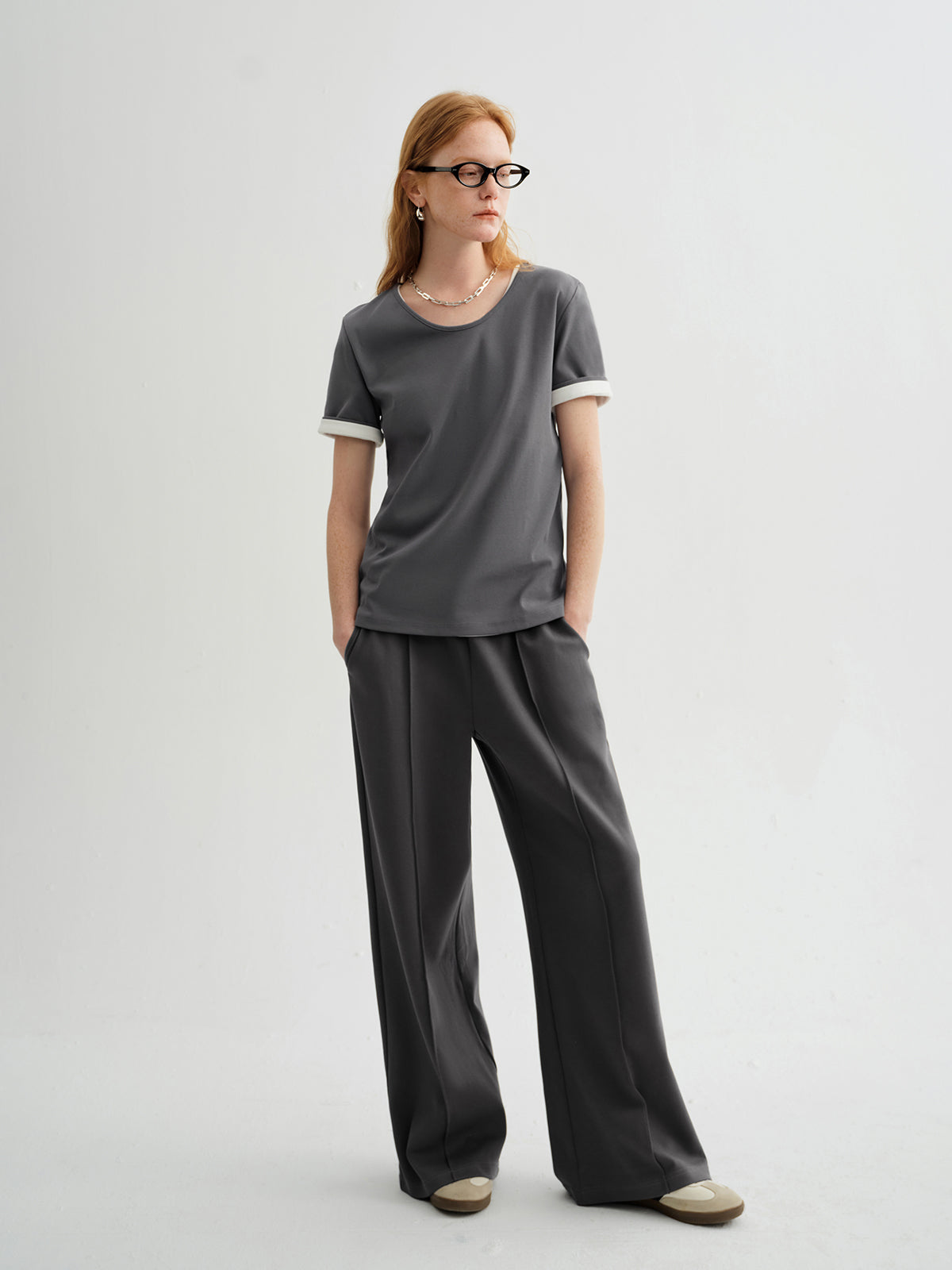 Woman wearing a gray t-shirt and wide-leg pants on a white background