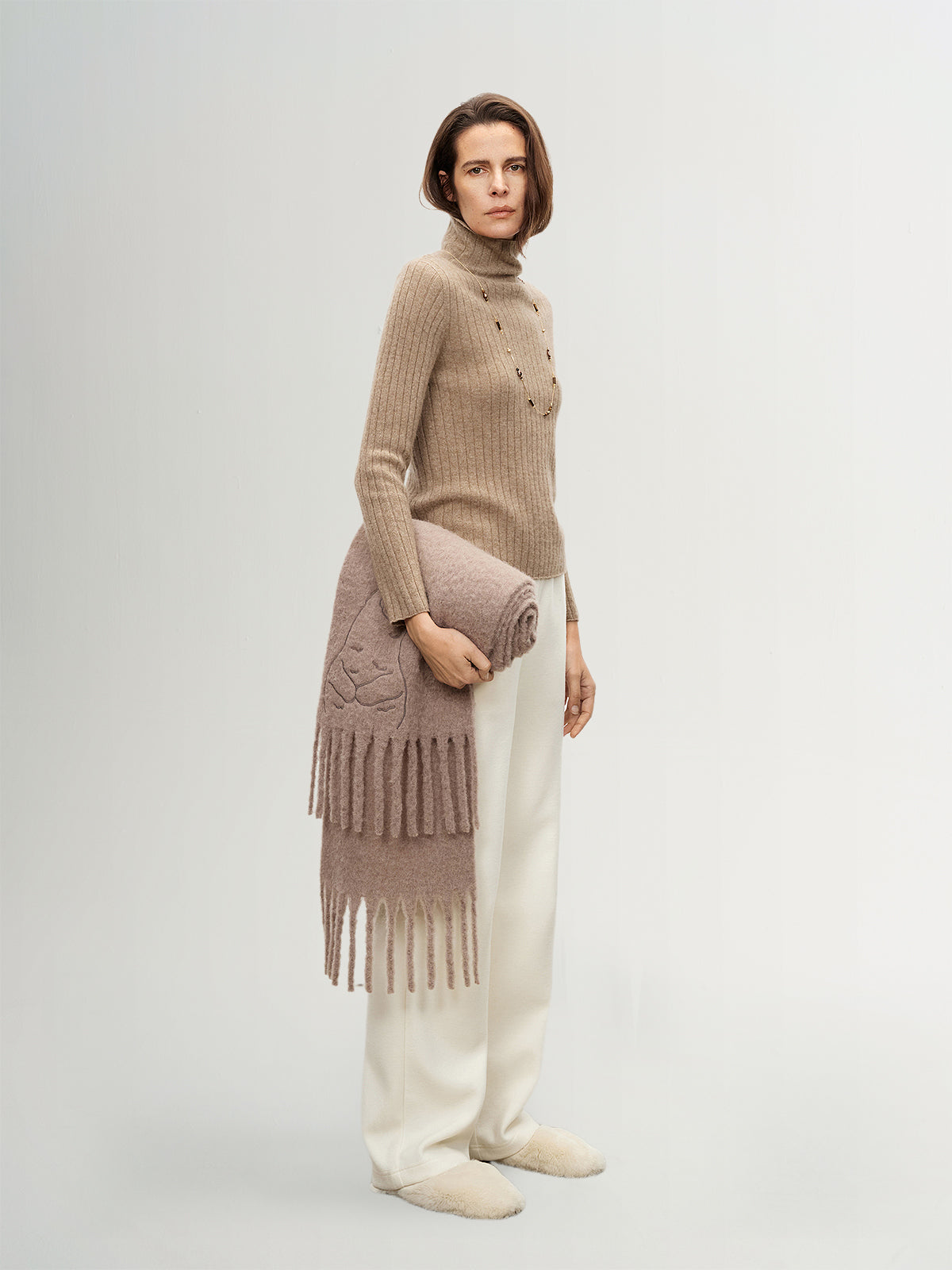 Woman holding a knitted scarf against a white background