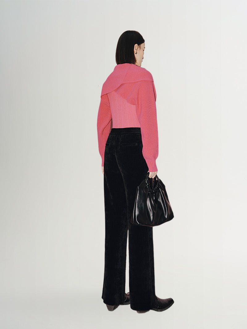 A model wearing wide leg trousers and a pink sweater, showcasing a stylish casual look from the back.