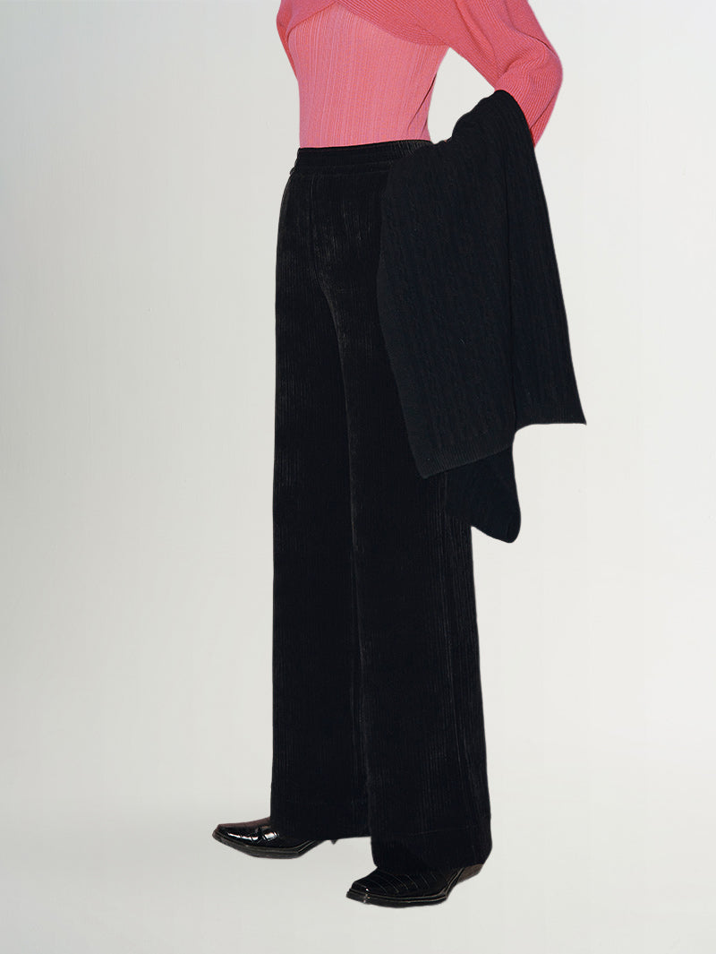 Wide Leg Trousers styled with a pink top and black shawl, showcasing a luxe velvet fabric and wide-leg silhouette.