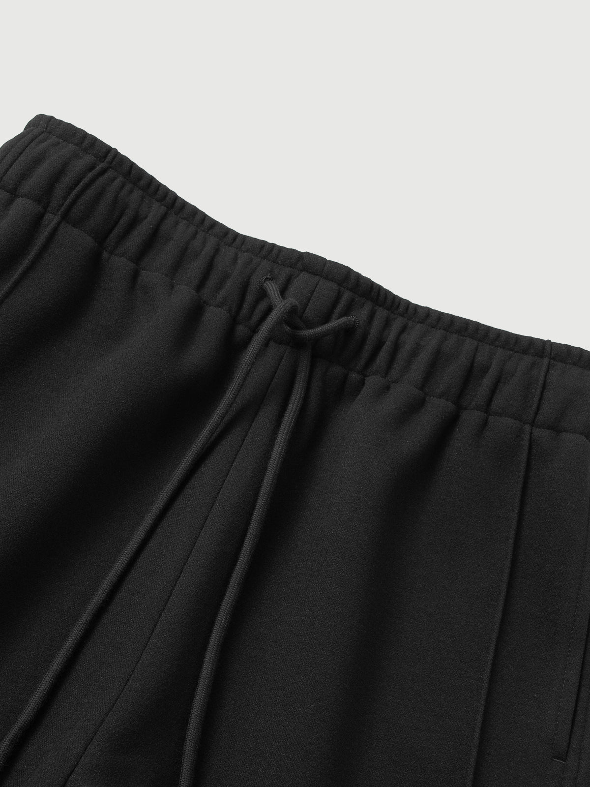 Close-up of black pants with an elastic waistband on a light gray background