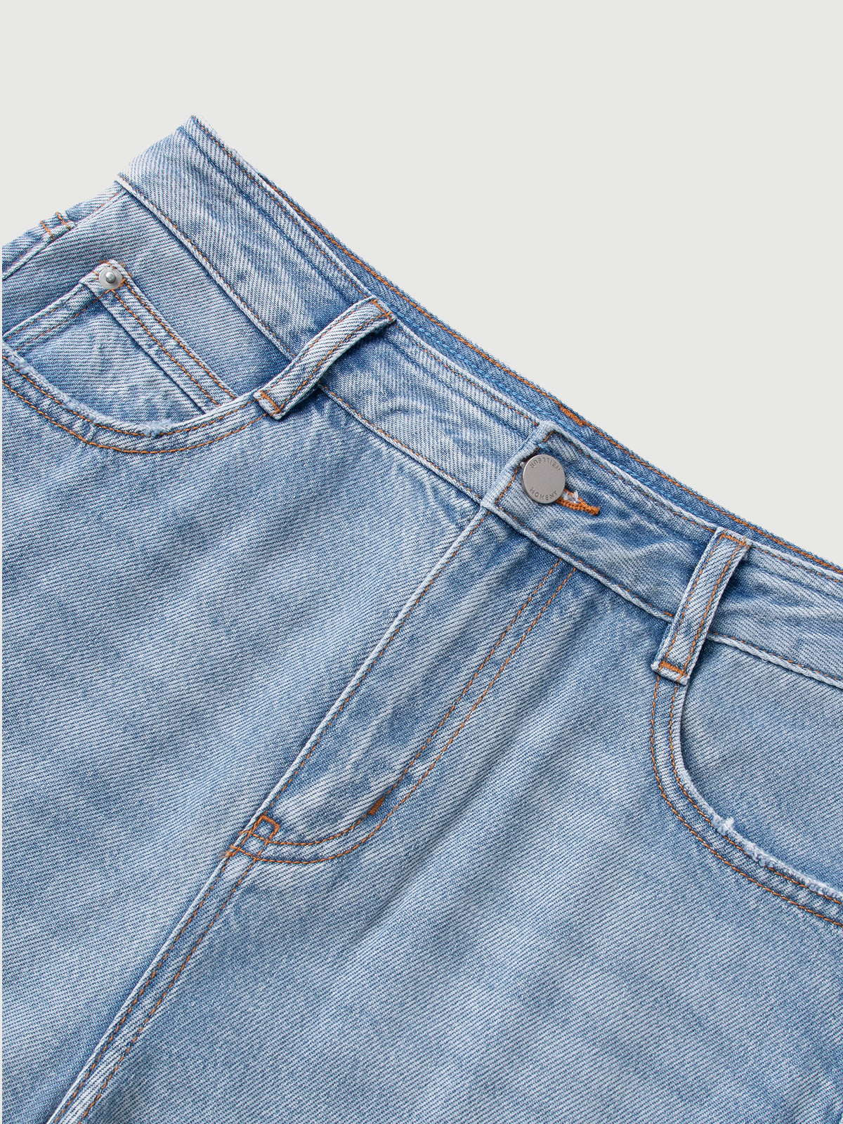 Close-up of a blue denim jeans pocket with brand logo on a light gray background