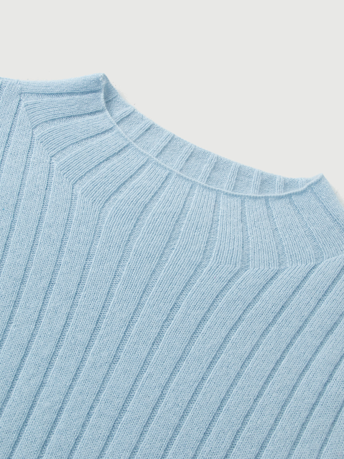 Close-up of a light blue ribbed sweater on a white background