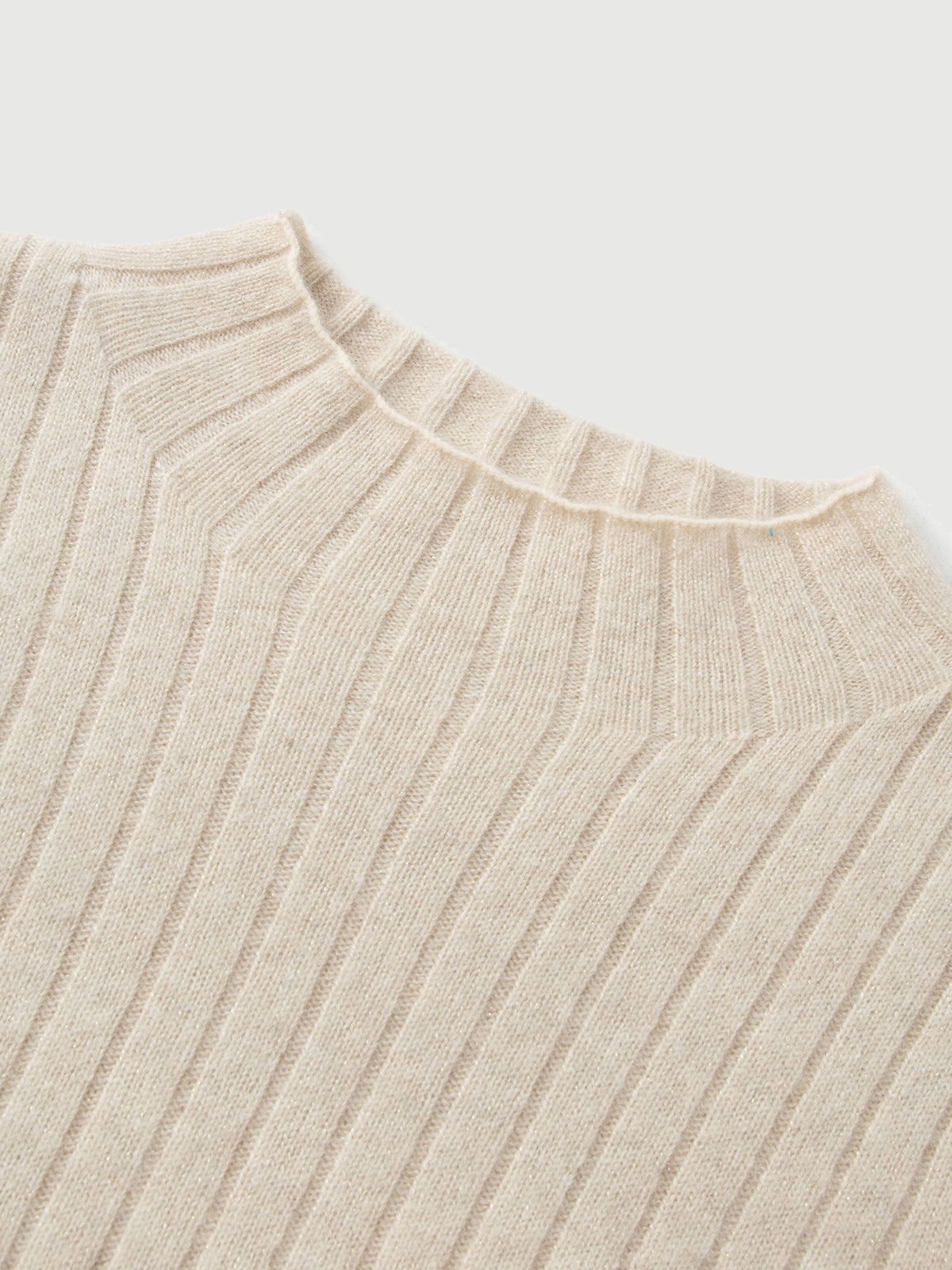 Close-up of a beige ribbed sweater on a light gray background