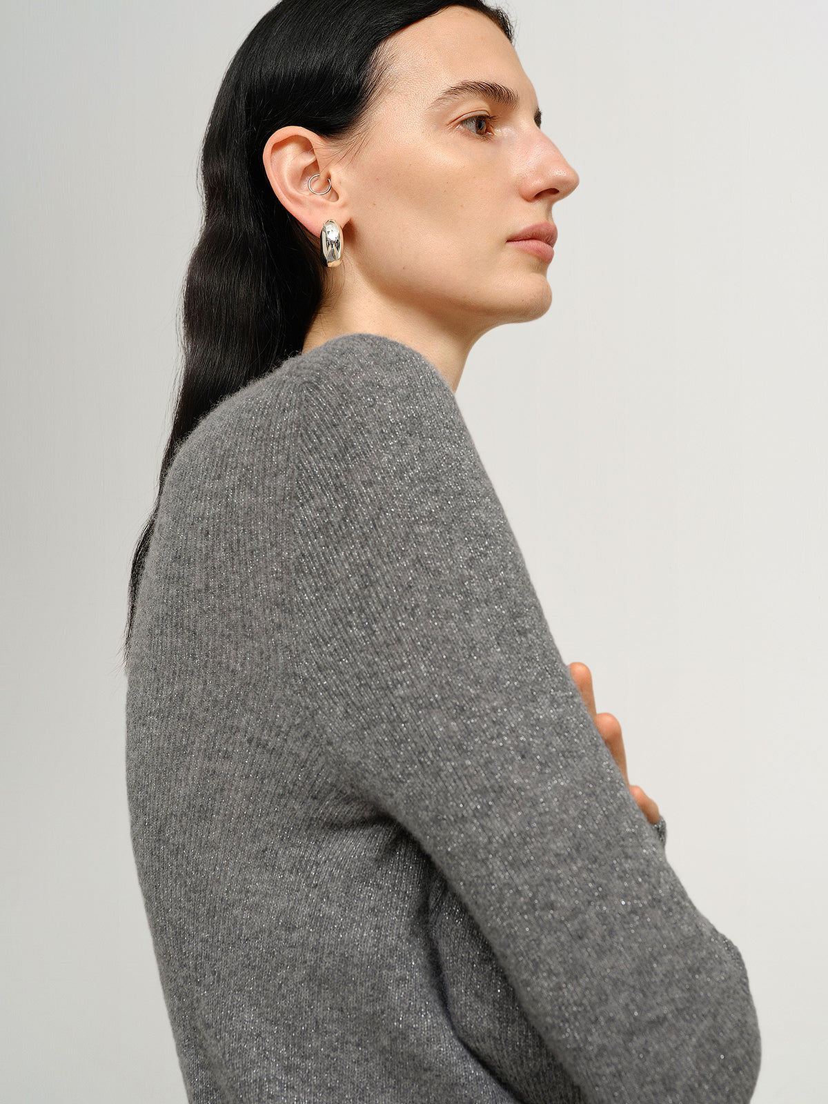 Woman wearing a gray sweater against a plain background