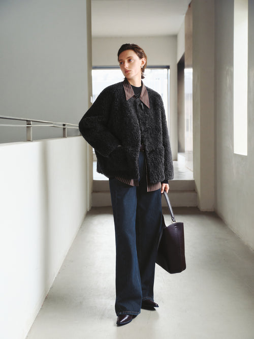 Load image 1 in gallery view. Person wearing a dark sweater and pants, holding a bag in a modern indoor setting