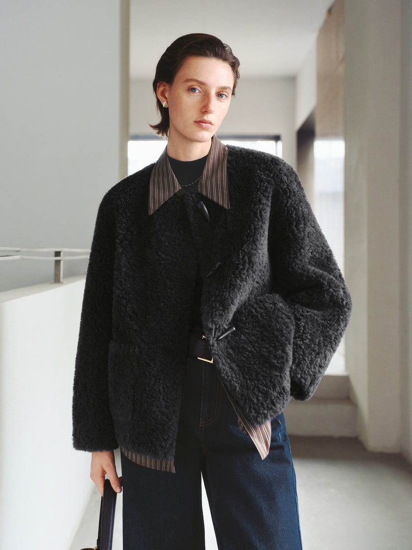 Person wearing a dark textured coat in an indoor setting