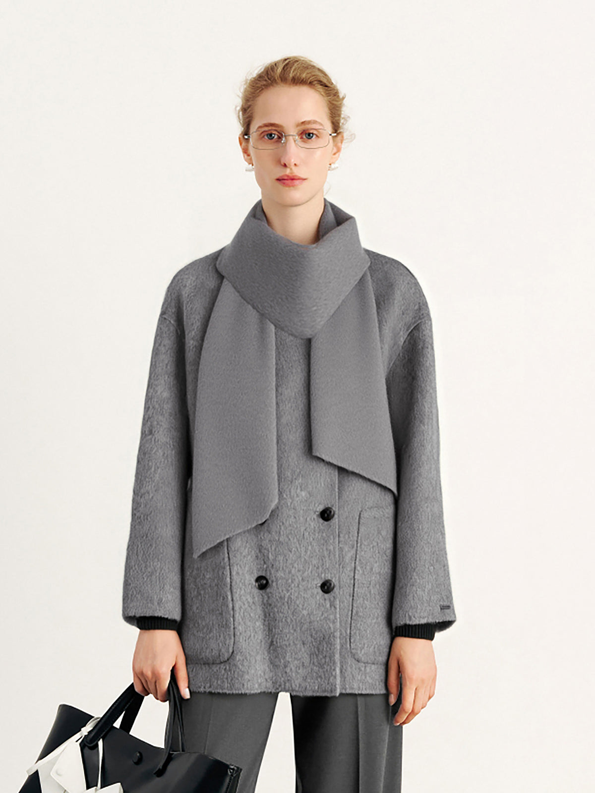 Woman wearing a gray coat with a large scarf on a white background