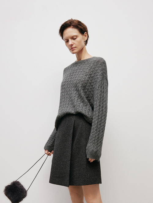 Load image 1 in gallery view. Woman wearing a gray knitted sweater and skirt holding a black fluffy object against a white background