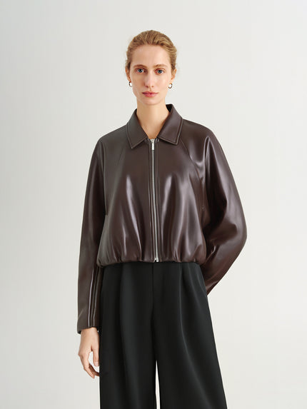 Woman wearing a brown leather jacket on a light gray background