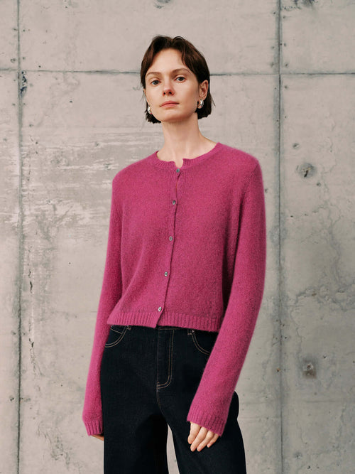 Load image 1 in gallery view. Silk-Cashmere Cardigan in vibrant pink, styled with dark jeans against a textured backdrop.