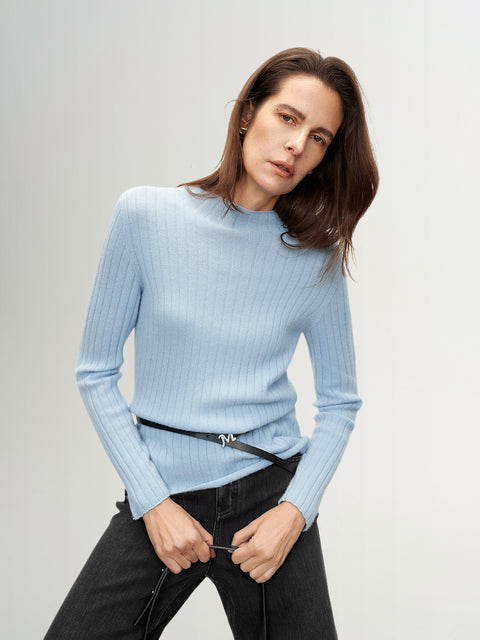 Woman wearing a light blue ribbed sweater against a plain background