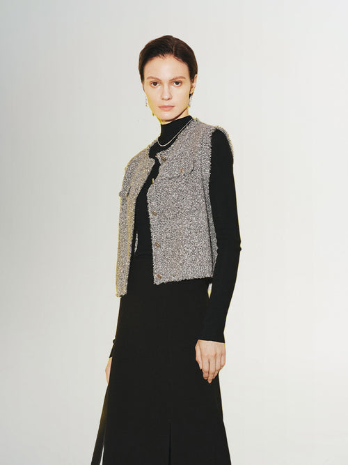 Load image 1 in gallery view. A woman wearing a gray tweed knit vest over a black top and a long black skirt.
