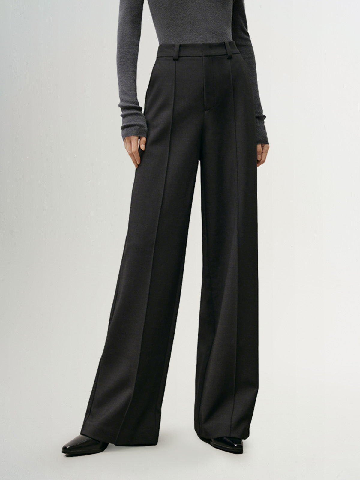 A woman wearing straight-fit high-waist trousers in a tailored design, offering a sleek and sophisticated look for any occasion.