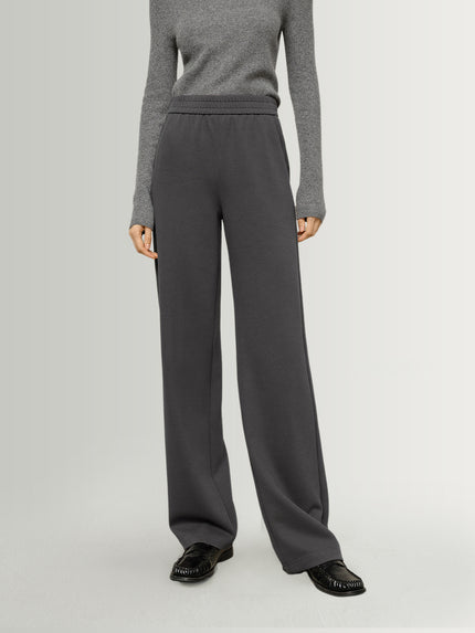 Person wearing gray sweater and dark gray pants on a light gray background