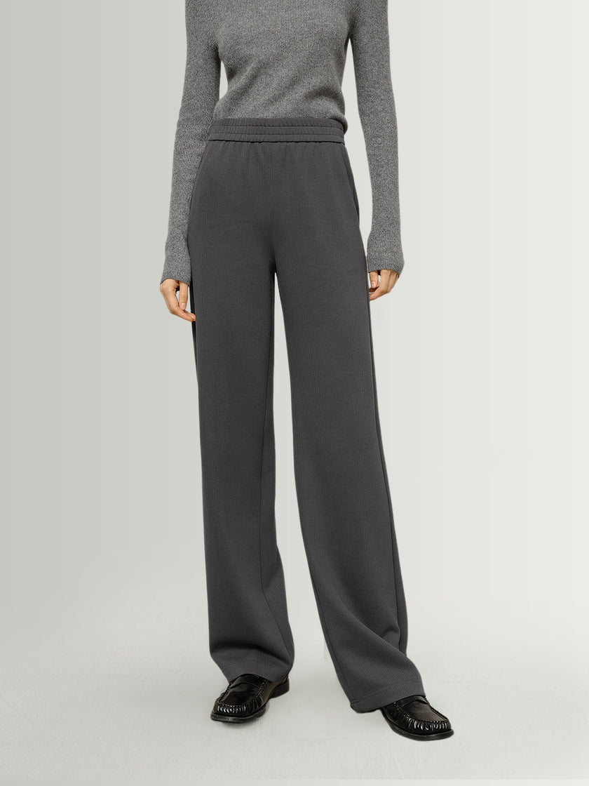 Person wearing gray sweater and dark gray pants on a light gray background