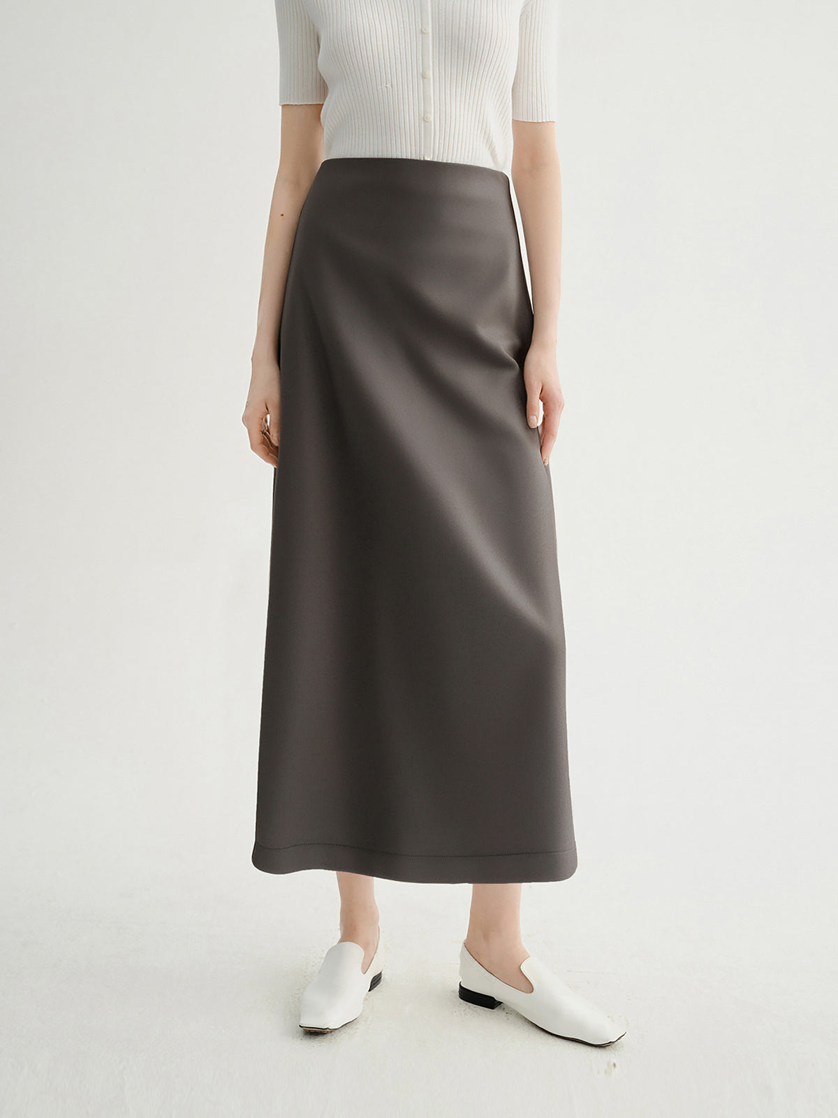 Person wearing a brown skirt and white top on a light gray background