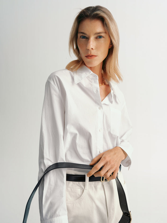 Women's  wearing a pure cotton classic collar shirt in white, styled with wide-leg trousers and a black belt, showcasing a clean and professional look.