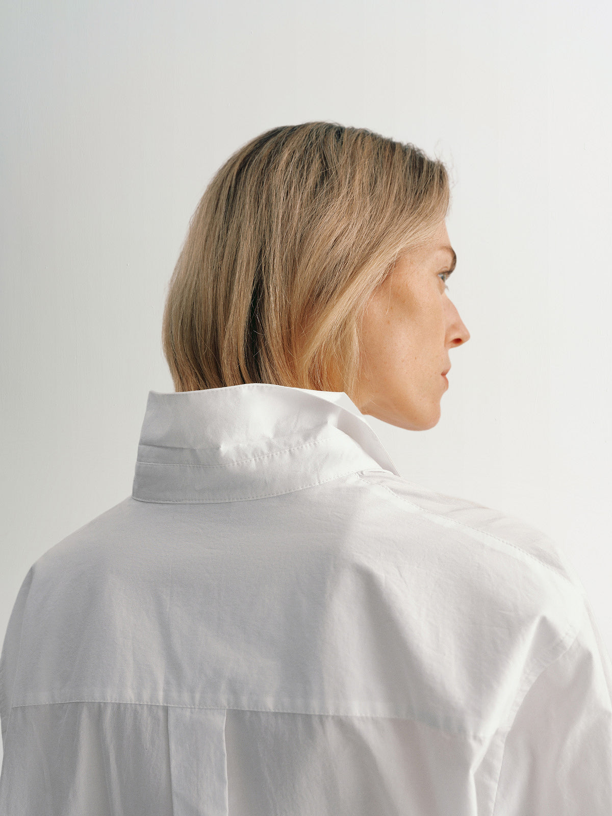 A woman showing the back of a Pure Cotton Shirt with a classic collar, embodying style and comfort.