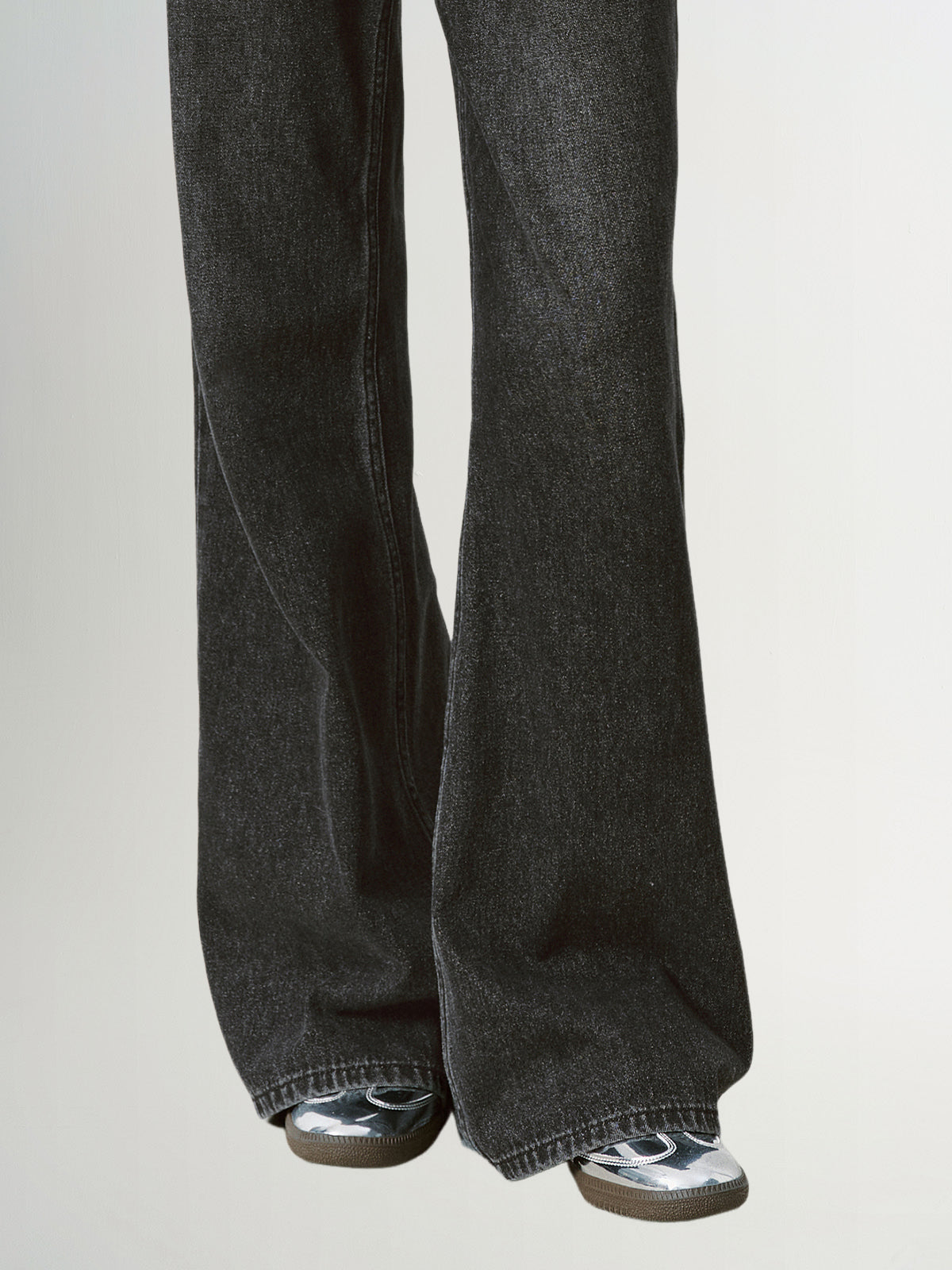 Black flared jeans worn by a person on a light gray background