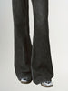 Black flared jeans worn by a person on a light gray background