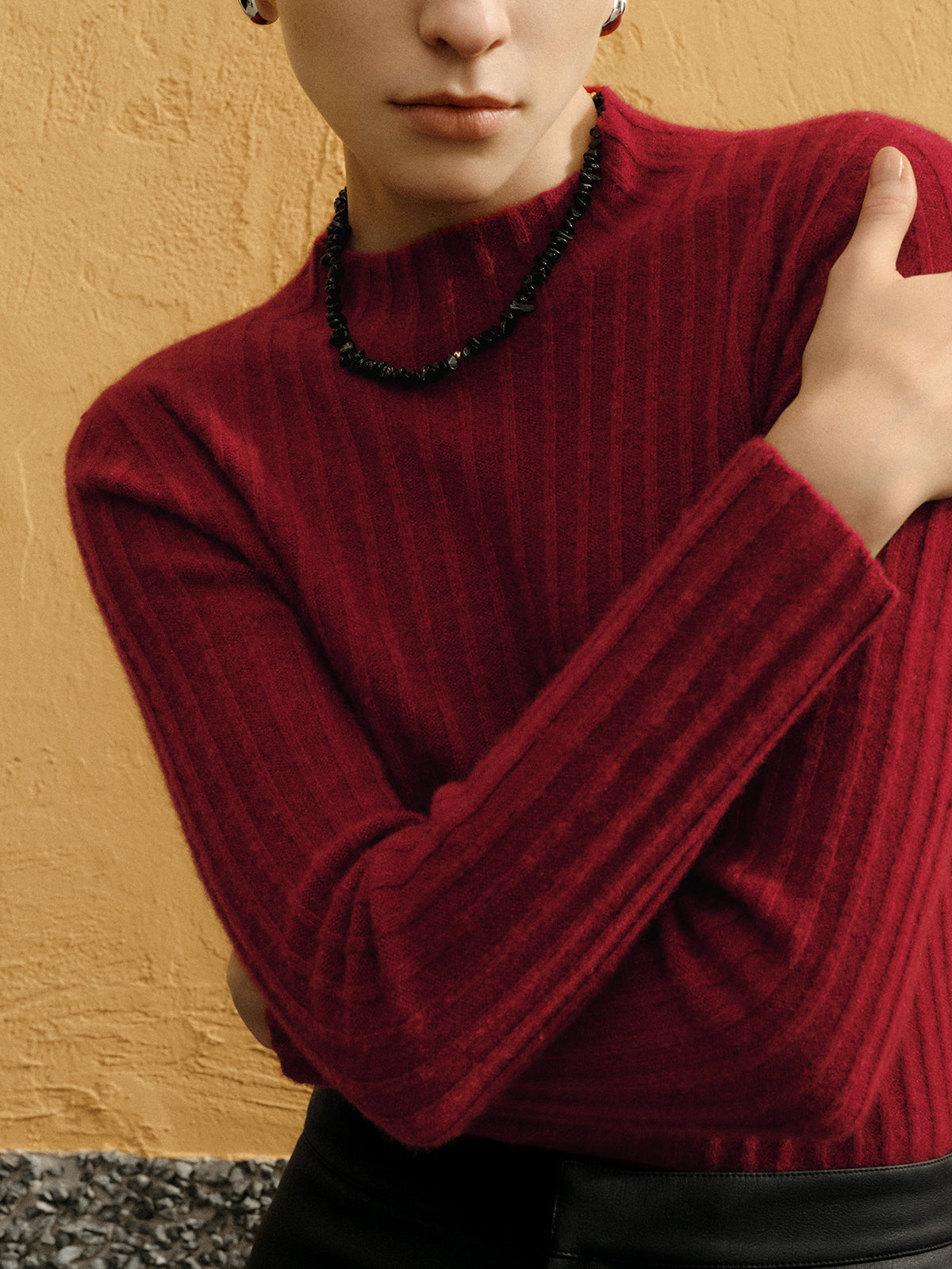 Person wearing a red sweater against a beige wall