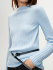 Light blue ribbed sweater worn by a person on a plain background