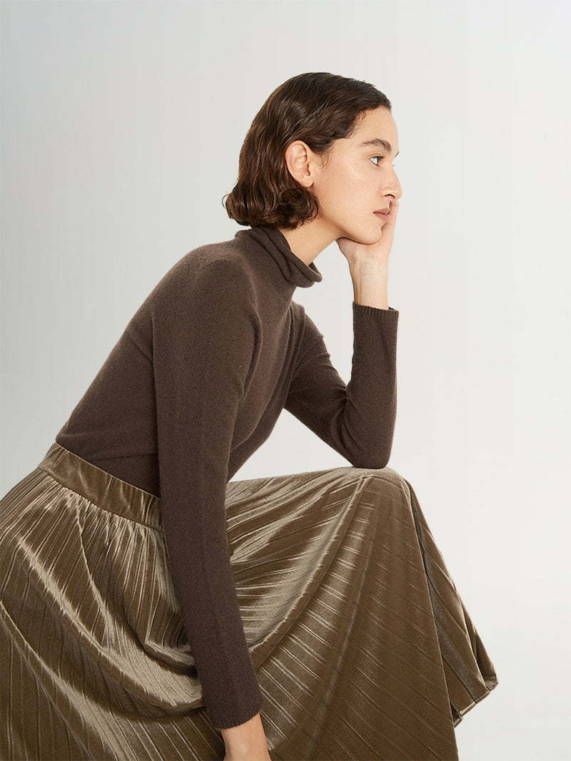 Model wearing a brown slim fit cashmere sweater, styled elegantly with a pleated metallic skirt.