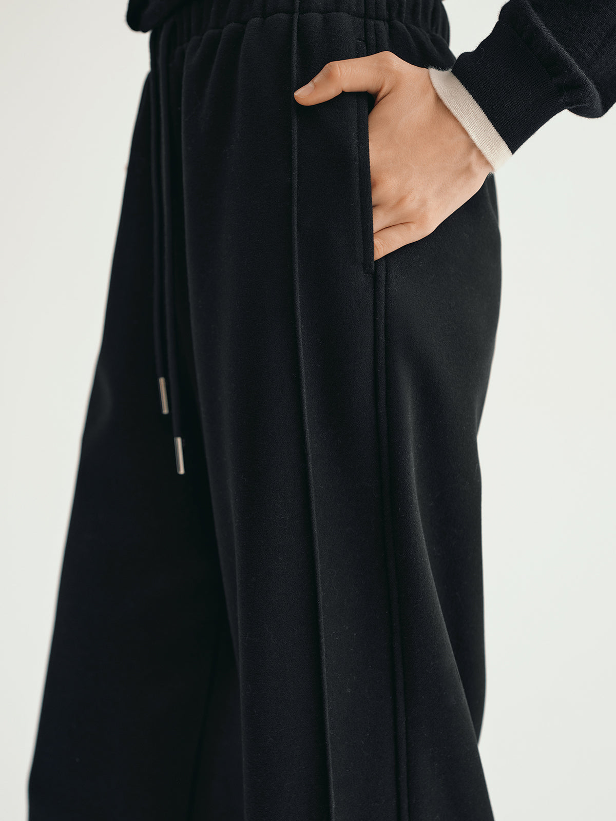 Black pants with a hand in the pocket on a light gray background