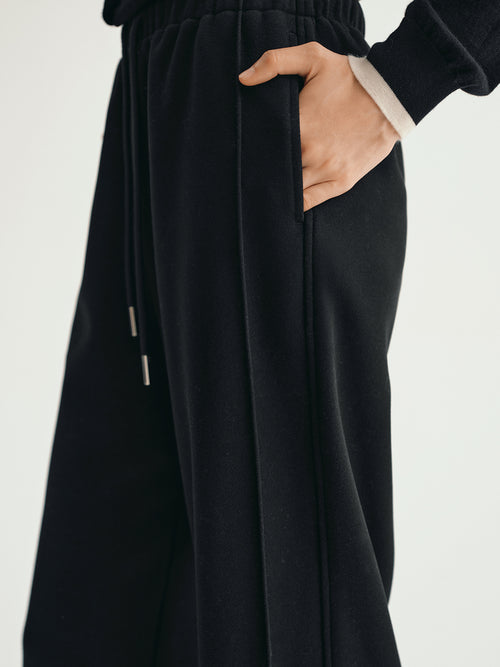 Load image 1 in gallery view. Black pants with a hand in the pocket on a light gray background