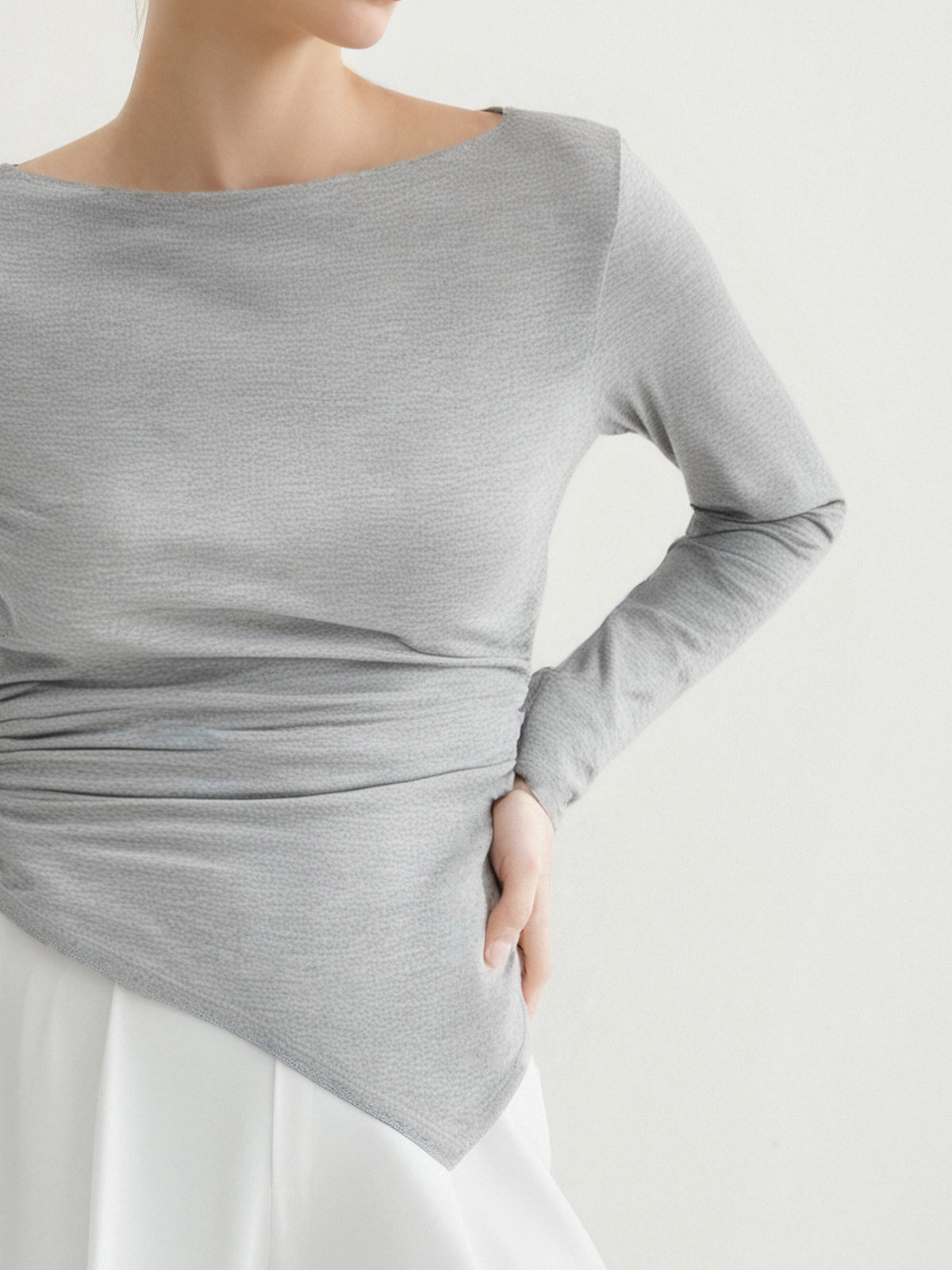 Gray long-sleeve top worn by a person on a white background
