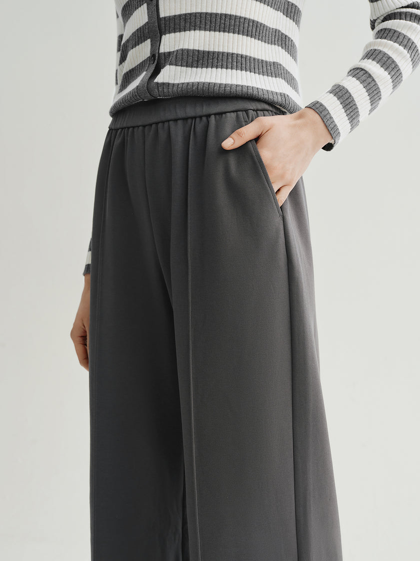 Person wearing gray wide-leg pants and a striped sweater on a light gray background