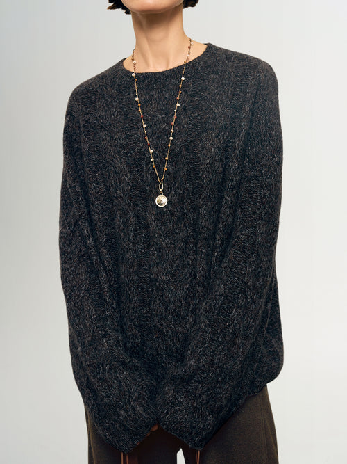 Load image 1 in gallery view. Person wearing a dark gray sweater and a long necklace with a pendant on a light gray background