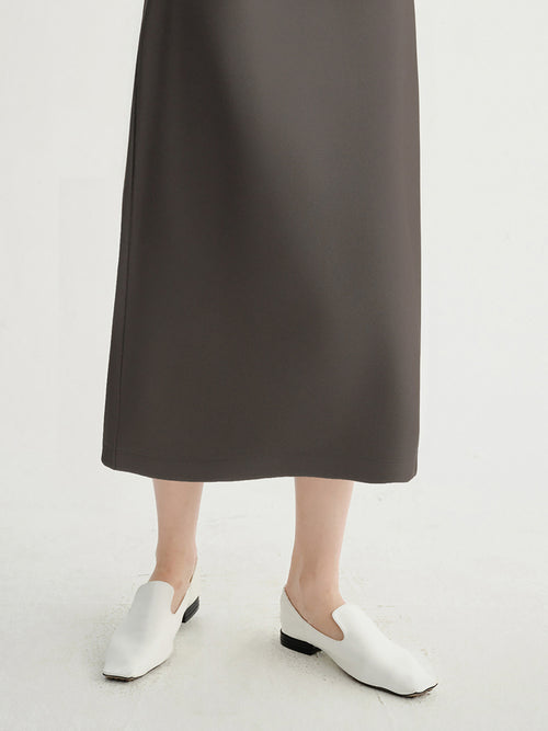 Load image 1 in gallery view. Person wearing a dark gray skirt and white shoes on a light background