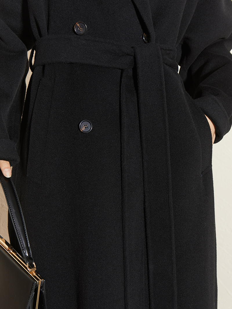 Close-up of a black coat with buttons on a neutral background