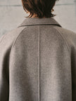 Person wearing a gray coat with a neutral background