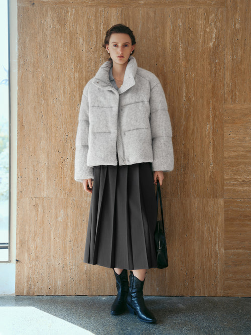 Load image 1 in gallery view. Woman wearing a light gray textured jacket and dark skirt against a wooden wall.