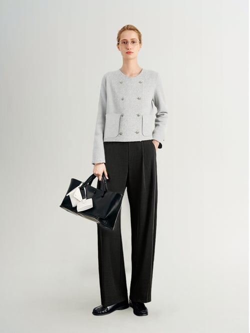 Load image 1 in gallery view. Person wearing a light gray sweater and black pants, holding a black handbag with a white bow on a white background