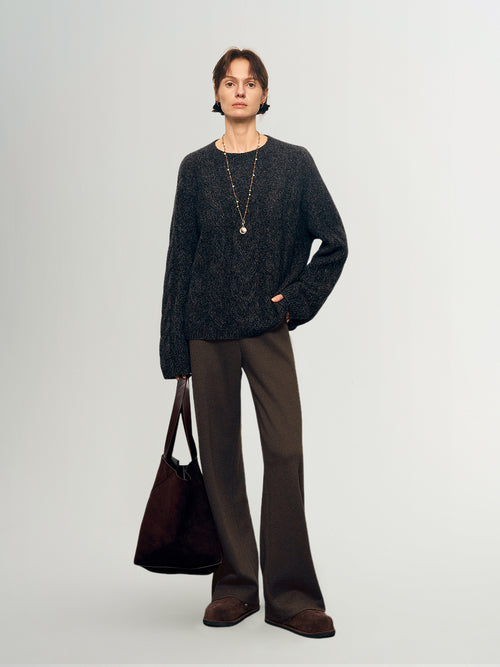 Load image 1 in gallery view. Person wearing a dark sweater and brown pants holding a brown bag on a light gray background