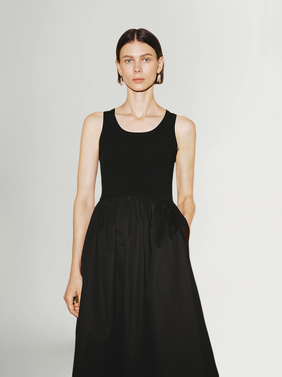 Woman wearing a black sleeveless dress against a plain background