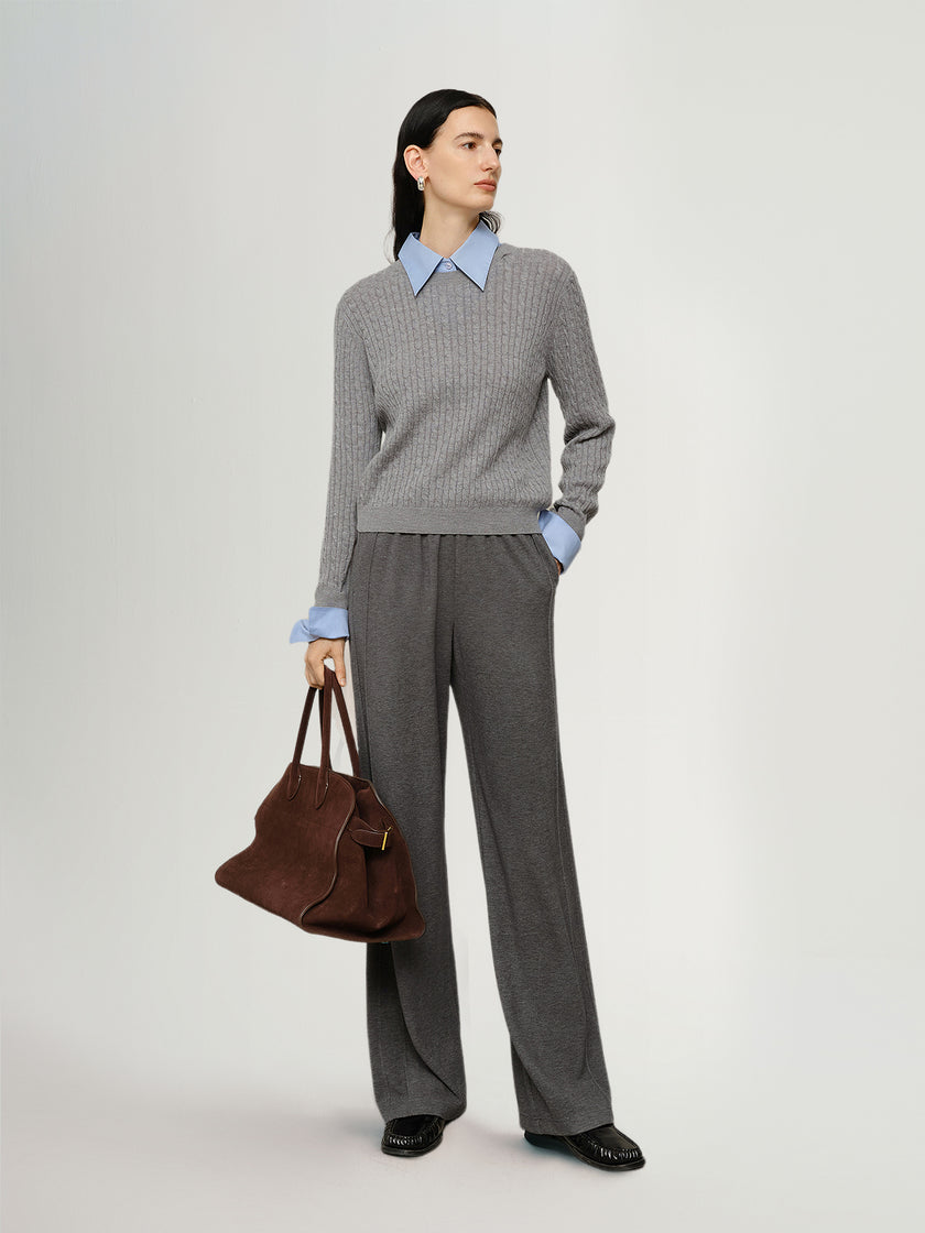 Woman wearing a gray checkered outfit with a brown bag on a white background