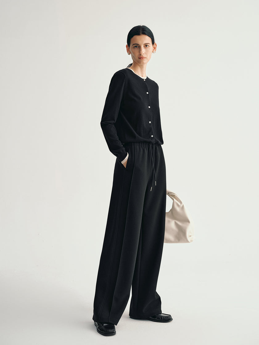 Person wearing a black outfit with wide-leg pants on a light gray background